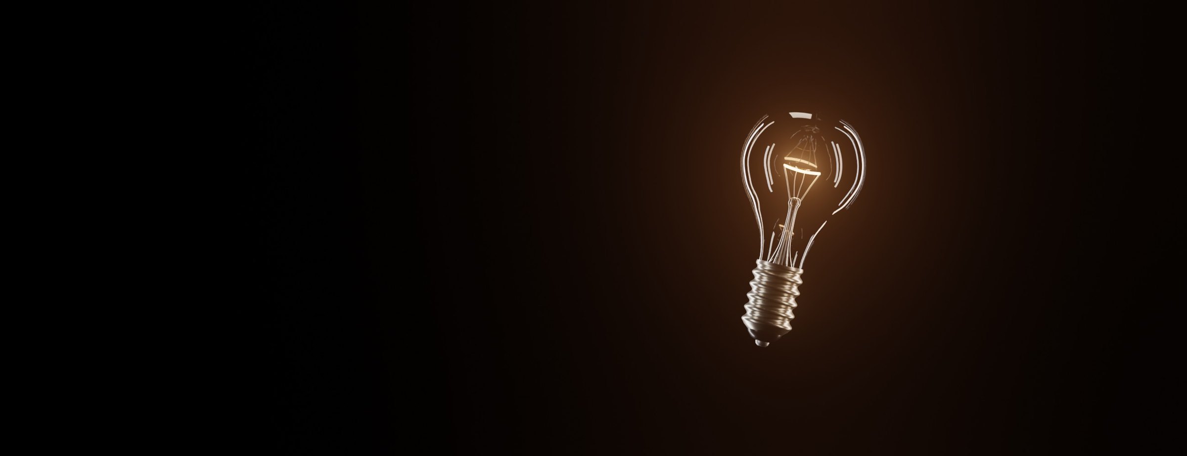 A lit incandescent light bulb floating in the dark